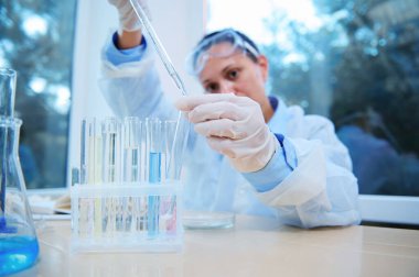Details: hands of a pharmacologist, scientist biologist, lab assistant using a graduated pipette, titrate the reagent into test tubes during a scientific experiment in a clinical research laboratory