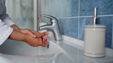 Close-up of a woman squeezing antibacterial soap from a soap dispenser, using a bathroom sink faucet and washing her hands. Hygiene, health, sanitation. Virus Prevent Spreading and Epidemic Outbreak.