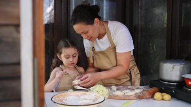 Patates püresi ve doğranmış dilli Vaneriki ile doldurulmuş ev yapımı Ukrayna hamur tatlısı pişirme kursu. Anne ve kızı yazlık mutfakta birlikte yemek pişiriyorlar.
