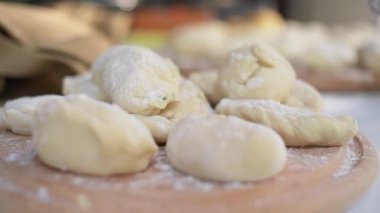 Seçici odaklanma. Ev yapımı hamur köftelerinin yakın çekimi, ahşap bir tahtanın üzerindeki Ukraynalı Varenyky, kırsal bir yazlık mutfakta elektrikli ocakta kaynar su bulunan bir tencereye odaklanıyor.