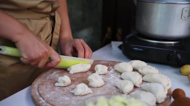 一个家庭主妇剪下面团做饺子 用滚动式别针铺开 用土豆泥做模子 做成自制的乌克兰瓦里基 乌克兰的传统国菜 — 图库视频影像