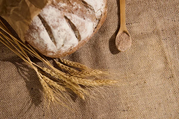 俯瞰全麦面包的全麦美味自制面包 丰富的纤维 撒满了白粉 麦片和一个木制勺子与麸皮在麻布桌布上 有选择的重点 — 图库照片
