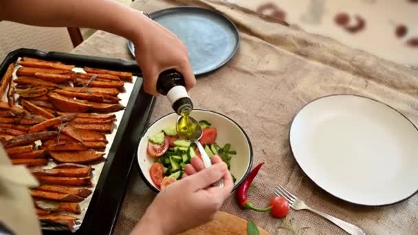 家庭主妇把橄榄油倒在西红柿和黄瓜片上 在家里厨房里准备蔬菜沙拉 一片烤好的烤好的薄片 上面铺着一块亚麻布桌布 上面放着炸红薯 顶部视图 — 图库视频影像