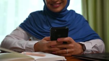 Orta Doğu kökenli, akıllı telefon kullanan, mesaj atan, haber kaynaklarını kontrol eden, web sitelerini karıştıran mavi tesettürlü güzel bir Müslüman kadının ellerine odaklan. Çevrimiçi iletişim.