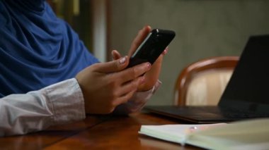 Ayrıntılar: akıllı telefon kullanan Müslüman kadın elleri, haber akışını kaydıran, içeriği kontrol eden, web sitelerini gezen, çevrimiçi alışveriş yapan, evden uzakta çalışırken rezervasyon yapan eller. Uzaktan iletişim.