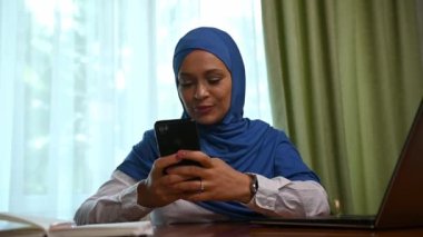 Çekici, kendine güvenen, orta yaşlı, tesettürlü, resmi giyinmiş, cep telefonu kullanan, haber yayını yapan, web sitelerini karıştıran, sosyal medyadaki içeriği kontrol eden, mesaj yazan,