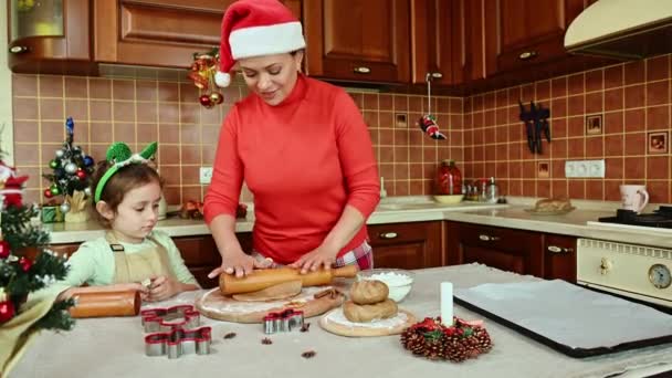 幸せな母親と娘はクリスマスのために一緒に自家製おいしいジンジャーブレッドクッキーを調理します かわいいです白人の女の子切断金型とき彼女の愛するお母さんロールアウトザ生地 でザホームキッチン — ストック動画