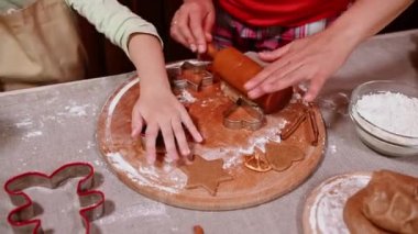 Anne ve kızının ellerinin merdane kullanışının, hamur hamurunu yuvarlamasının, kurabiye kesicinin ve ev yapımı zencefilli kurabiye pişirirken hamurdan şekil alışının en üst görüntüsü. Noel pastanesi