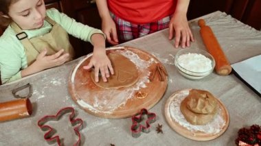 Kafkasyalı küçük güzel bir kızın hamurun üzerine kurabiye keskisi koyması, küfleri kesmesi, annesiyle hazırlanması, Noel için ev yapımı lezzetli zencefilli kurabiyeler.