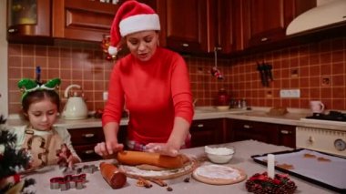 Yuvarlak iğne kullanan annelerin ellerine odaklan. Ev mutfağında zencefilli kurabiyeler için hamur ayır. Elf çemberindeki küçük kız kurabiye kesicilerle oynuyor, annesiyle yemek pişirmekten hoşlanıyor.