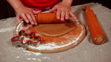 Yuvarlak iğne kullanan, hamur hamurunu yuvarlayan, hamuru kesen ve ev yapımı zencefilli kurabiye pişirirken hamurdan şekil alan kadınların el manzarası. Noel pastanesi