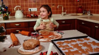 Bej bir şef önlüğü takan, güzel, yaramaz beyaz kız zencefilli ekmek hamuruyla oynayıp ev yapımı lezzetli Noel kurabiyeleri hazırlıyor. Noel Zamanı