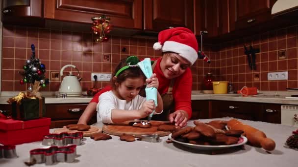 Madre Cariñosa Con Sombrero Santa Pie Junto Adorable Hija Enseñándole — Vídeos de Stock