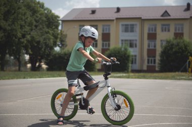 Okul çağındaki çocuk şehirde aşırı numaralar ve bisiklet öğreniyor. Bisiklet süren, asfalt yolda bisiklet süren koruyucu kıyafetli bir çocuk. Spor. Aktif, sağlıklı yaşam tarzı konsepti