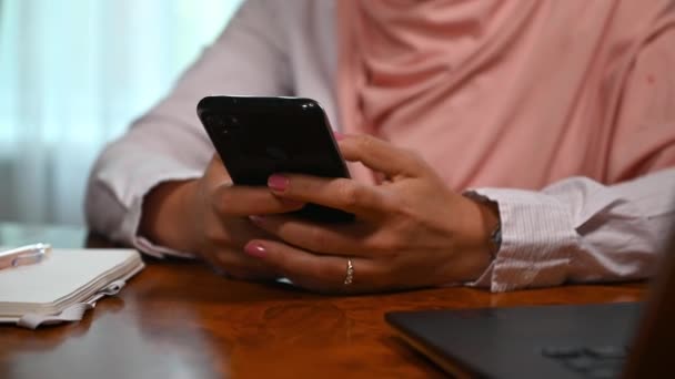 切り取られた景色 認識できないイスラム教徒の女性の手に焦点を当て ピンクのヒジャーブを着て スマートフォンを使用して ニュースフィードをスクロールし スワイプし ソーシャルメディアでコンテンツをチェックし ネットワーキング — ストック動画