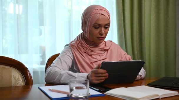 분홍색 히잡을 아름다운 이슬람 사무실에서 원격으로 테이블에 일하는 디지털 태블릿을 — 비디오