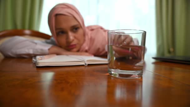 过度劳累的阿拉伯穆斯林妇女把一个泡腾腾的石碑放进一杯水里 中东妇女头戴头巾 感到筋疲力尽 用一杯水消解头痛止疼药片 — 图库视频影像