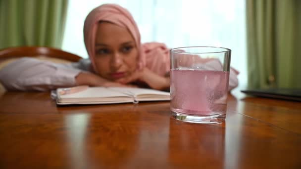 Blízkovýchodní Muslimka Hidžábu Sleduje Jak Šumivá Tableta Rozpouští Sklenici Vody — Stock video