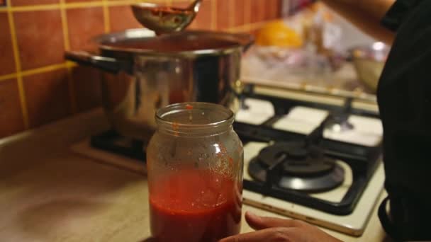 選択的フォーカス 滅菌された缶詰はキッチンカウンターの上に置くことができ シェフはキッチンスプーンを使用して 鍋から新鮮な醸造トマトジュースを注ぎ 有機トマトから自家製パスタを調理します — ストック動画