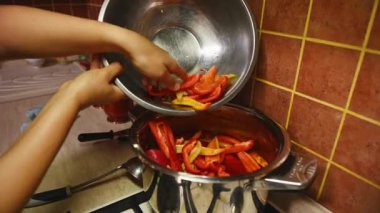 Ev hanımlarının elleri kaynar domates suyuyla dolu bir dereye olgun organik dolma biber döker ve kışın korunması için leço salatası hazırlar. Sebze konservesi. Yiyecek Koruması