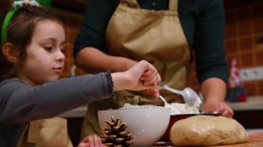 Bulanık anne ve kızının noel pastası için hamur yoğurmasına karşı bej benekli beyaz un tabağına seçici bir şekilde odaklan. Anne ve kızı birlikte yemek pişiriyor. Noel zamanı. Pişirme kavramı