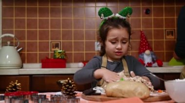 Elf halkası takmış güzel beyaz bir kız ve bej rengi bir önlük, geleneksel bir Alman pastası yapıyor- evdeki rahat ahşap mutfakta çalınmış. Arka planda kutulanmış Noel hediyesi