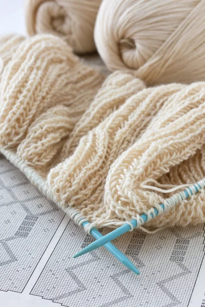 Tessuto lavorato a maglia e ferri da maglia su sfondo di carta — Foto Stock