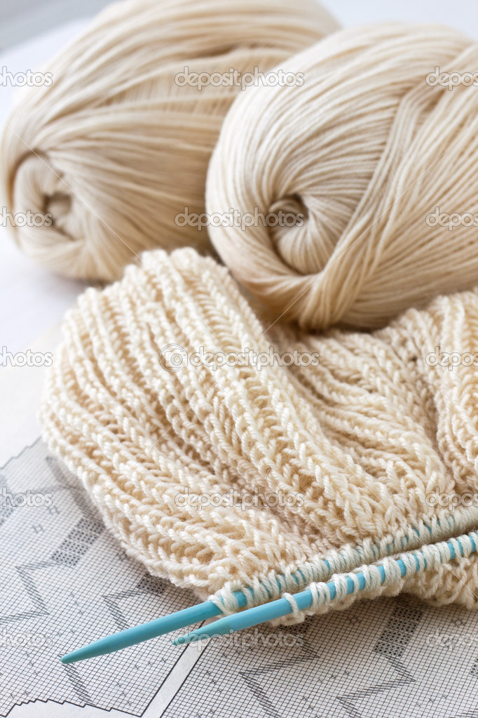 knitted fabric and knitting needles on a paper background