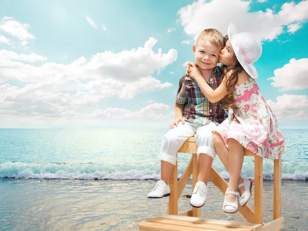 Lilla flickan kysser pojke på havet liggande vid solnedgången — Stockfoto