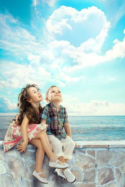 Kinder suchen blauen Himmel mit herzförmigen Wolken — Stockfoto