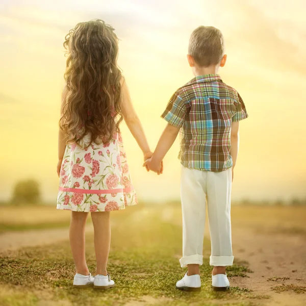 Vue arrière de petits enfants tenant la main au coucher du soleil — Photo