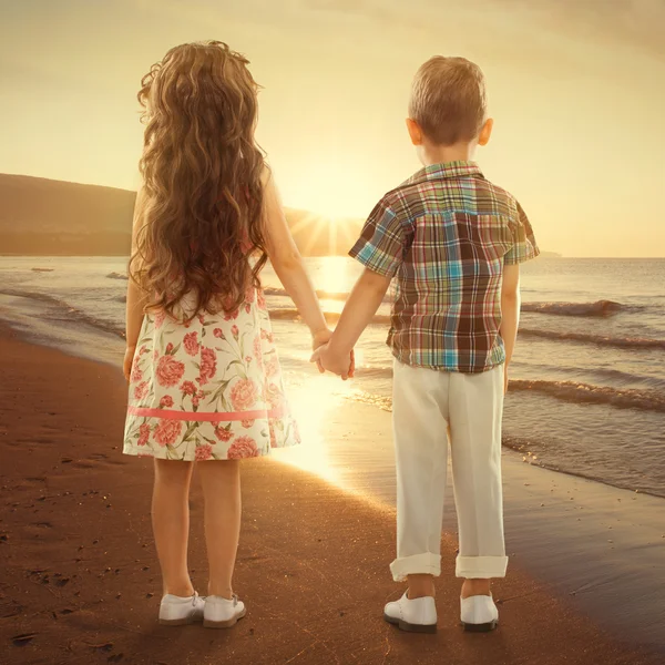 Achteraanzicht van kleine kinderen hand in hand bij zonsondergang — Stockfoto