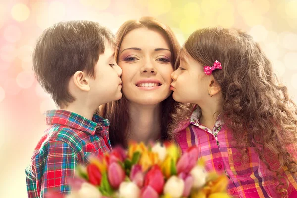 Happy mother kissed by her daughter and son — Stock Photo, Image