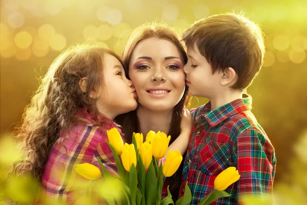 Mãe feliz beijada por sua filha e filho — Fotografia de Stock