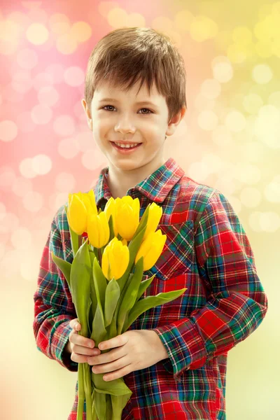 Smiling boy with a bouquet of yellow flowers — Stock Photo, Image