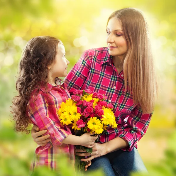 Daughter hugging his mother and gives her flowers — Stock Photo, Image