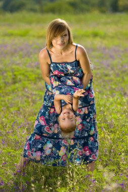 Happy mother playing with daughter in field clipart