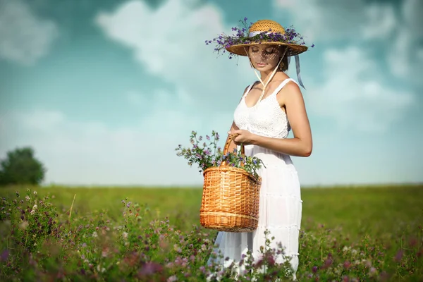 Vacker ung kvinna med blommor i fältet — Stockfoto