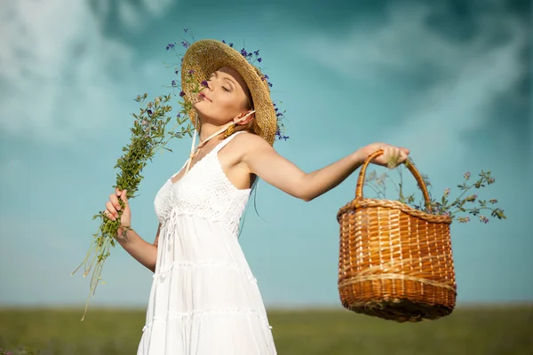 Hermosa joven con flores en el campo — Foto de Stock