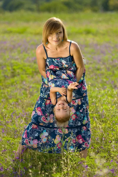 Lykkelig mor som leker med datter på jordet – stockfoto