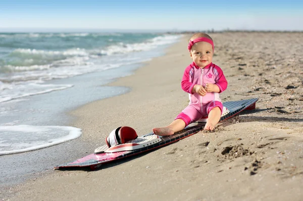 Liten flicka på sandstranden med surfbräda — Stockfoto