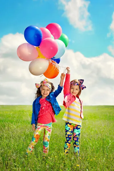 Kinderen met ballonnen lopen op lente veld — Stockfoto