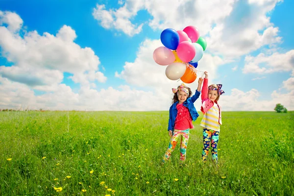 Kinderen met ballonnen lopen op lente veld — Stockfoto