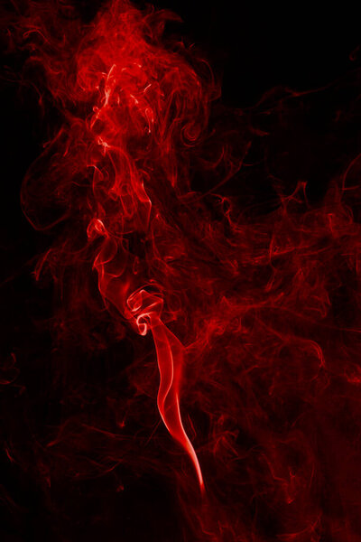Red abstract light smoke swirl background on black.
