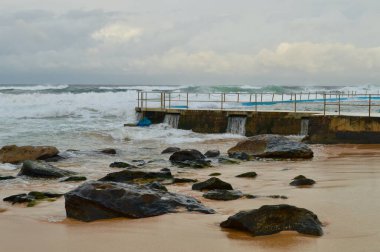 Dalgalar Sidney, Avustralya 'daki South Curl Sahili' ndeki kaya havuzuna çarpıyor.