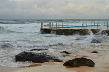 Dalgalar Sidney, Avustralya 'daki South Curl Sahili' ndeki kaya havuzuna çarpıyor.