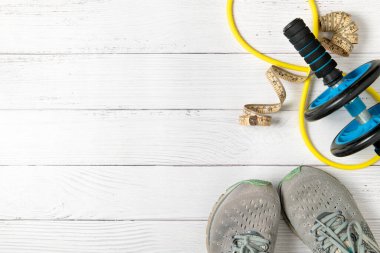 beyaz ahşap zeminde koşu ayakkabıları ve karın egzersizleri ve bel bandı. Kilo vermek için egzersiz kavramı.
