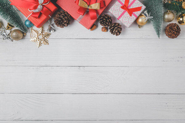 Christmas background with red gift and fir tree and decor on white wood background. Top view with copy space