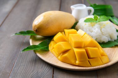 Ahşap tabakta hindistancevizi aromalı pilav ile olgun mango.,