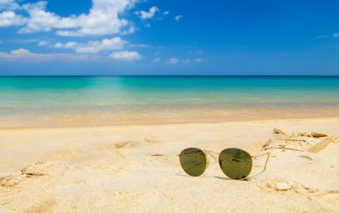 Sunglasses on sandy beach in summer and sea background, summer and travel concept